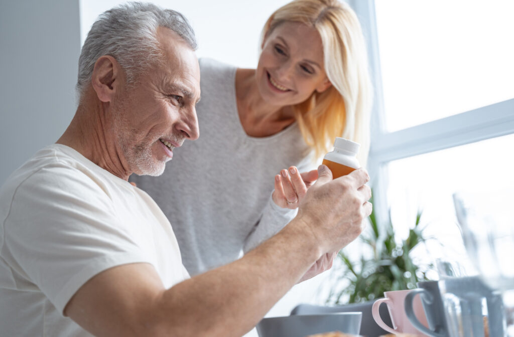elderly man looks at a pill bottle while his wife looks on