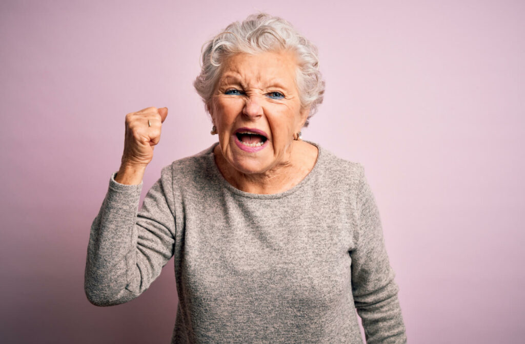 A senior woman with a clenched fist shouting with anger.